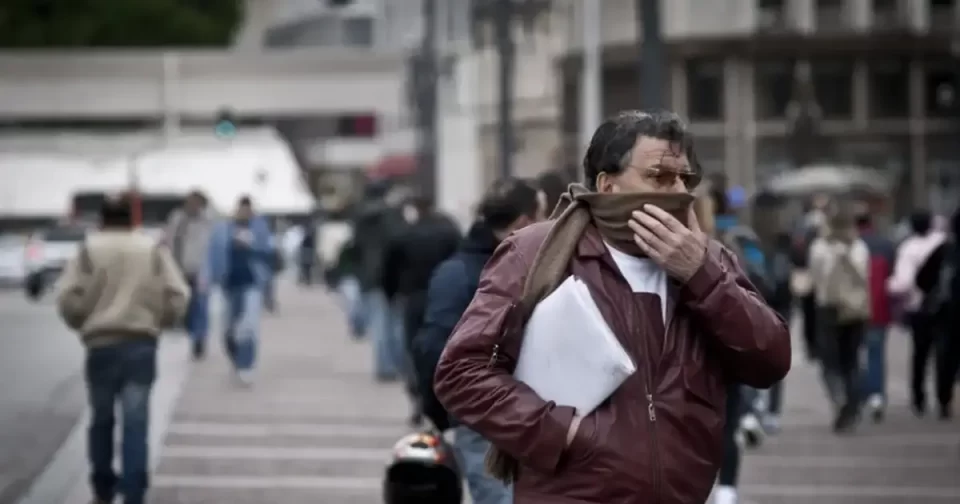 Homem na rua durante o inverno, com blusa pesada e cachecol.